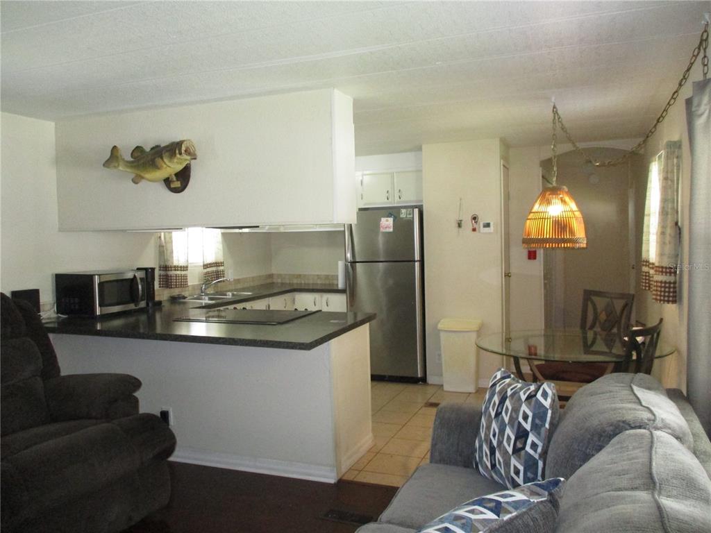 A kitchen with a breakfast bar, stainless steel refrigerator, and dining area with a pendant light — 92 ROSALIE OAKS BOULEVARD, LAKE WALES, FL