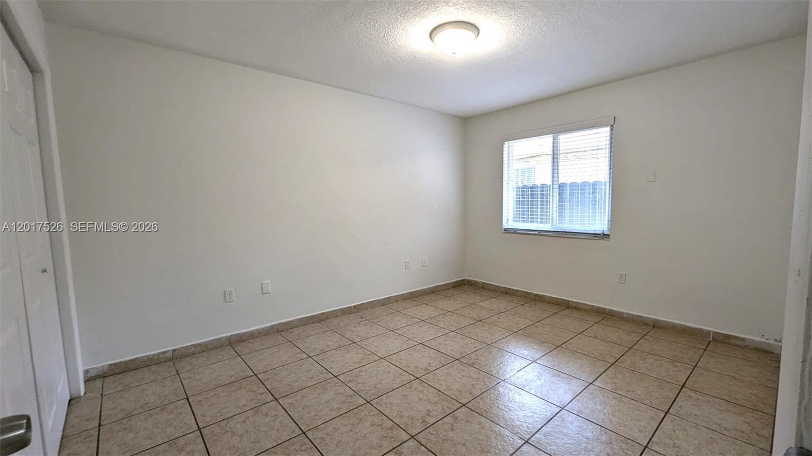 An empty bedroom features beige tile flooring, white walls, and a single window — 3525 SW 25th Ter # 1, Miami FL 33133, MIAMI, FL