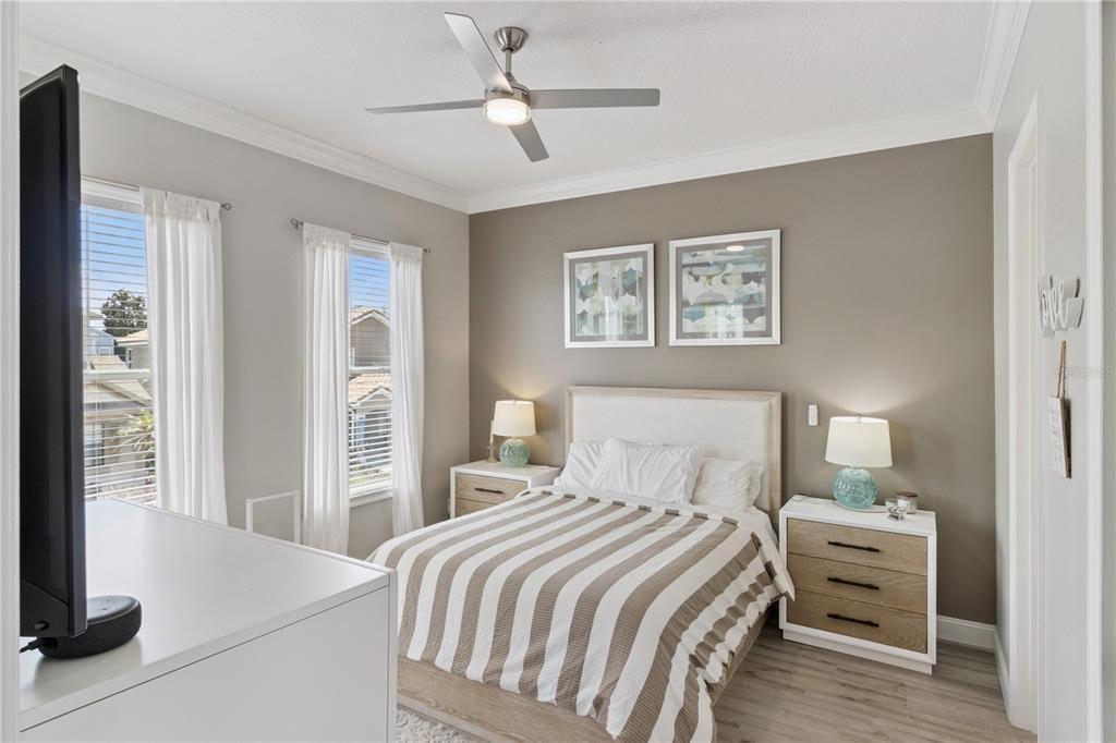 A bedroom features a bed with striped bedding, two nightstands, and a ceiling fan — 7407 OCONEE ST, REUNION, FL