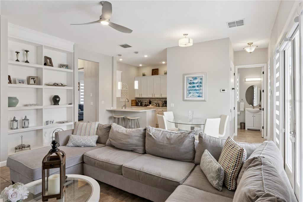 An open-concept living room features a large gray sectional sofa, built-in shelving, and a kitchen — 7407 OCONEE ST, REUNION, FL