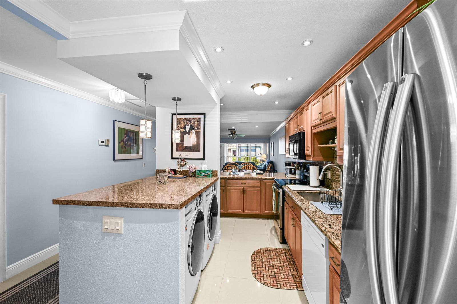 A kitchen features wood cabinets, granite countertops, stainless steel appliances, and an integrated laundry area — 2730 SW 15th Street # a, Delray Beach FL 33445, DELRAY BEACH, FL