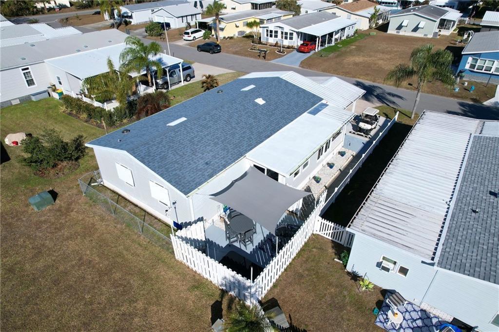 An aerial view of a manufactured home with a shingled roof and a fenced patio — 809 Lychee Drive, Barefoot Bay FL 32976, BAREFOOT BAY, FL