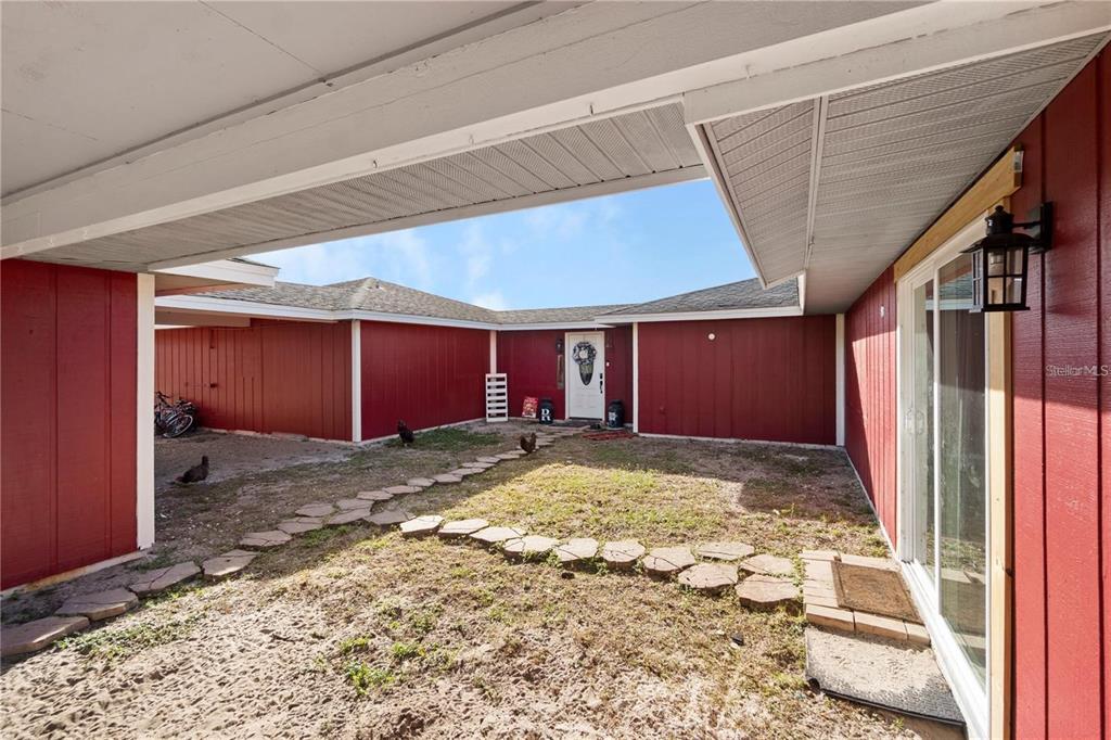 A red-sided house features a central courtyard with a stone path leading to the entrance — 15525 VILLA CITY ROAD, GROVELAND, FL