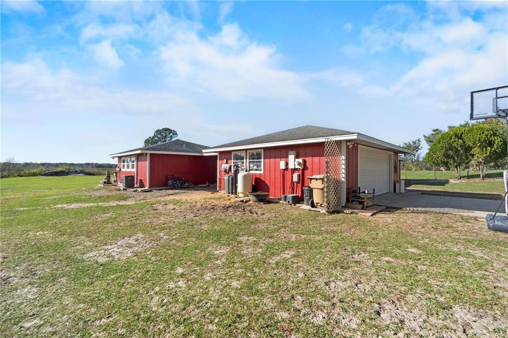 A red exterior building with a garage and a large grassy yard under a sky — 15525 VILLA CITY ROAD, GROVELAND, FL