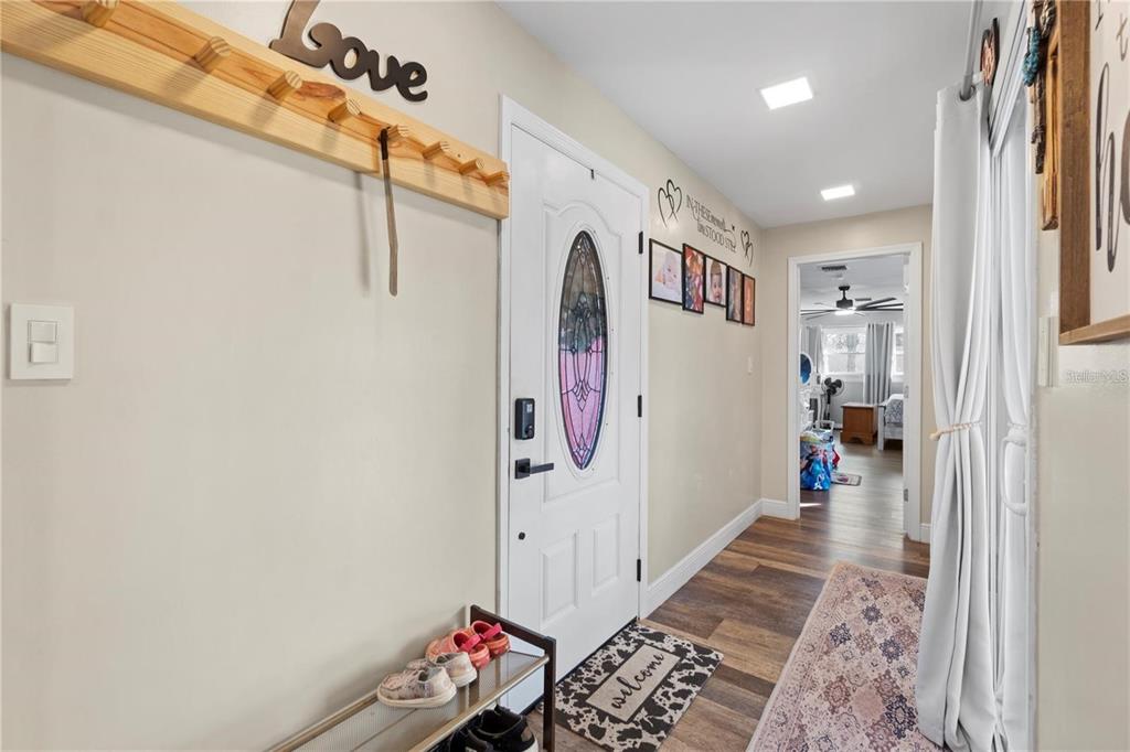 An entryway features a white front door, wood-look flooring, a coat rack, and a shoe rack — 15525 VILLA CITY ROAD, GROVELAND, FL