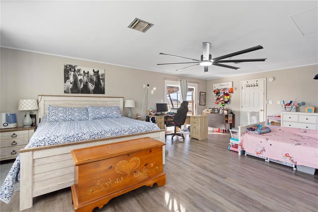 A bedroom features a large bed, a child's bed, a desk, and wood-look flooring — 15525 VILLA CITY ROAD, GROVELAND, FL