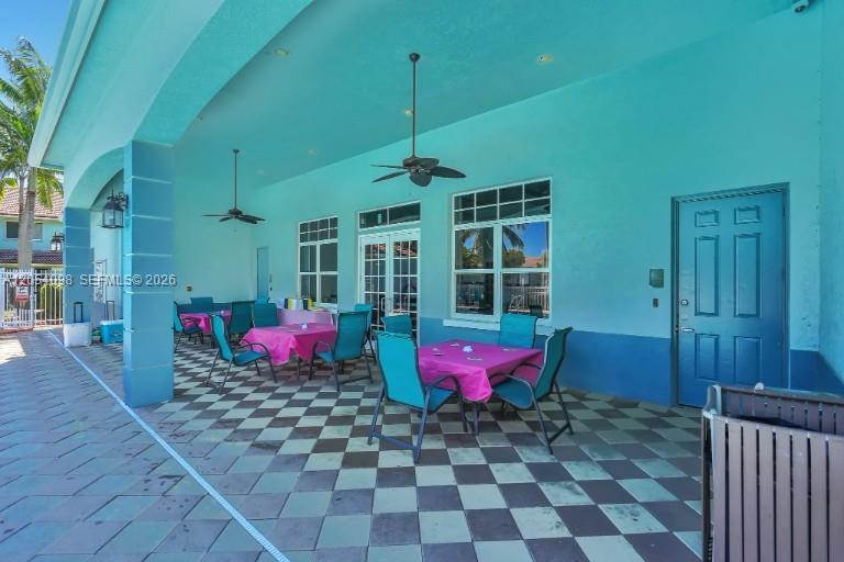 A covered outdoor patio features a checkered floor, teal walls, and several dining tables — 1942 Alamanda Way, Riviera Beach FL 33404, RIVIERA BEACH, FL