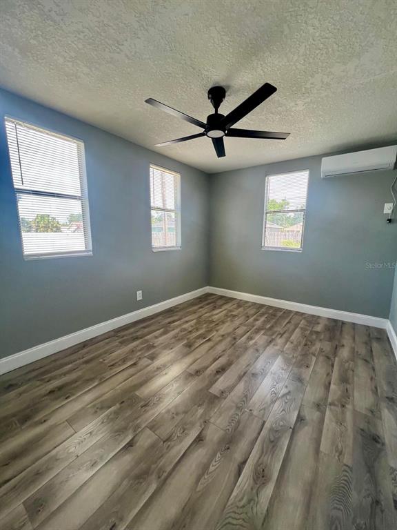An empty bedroom with gray walls, wood-look flooring, a ceiling fan, and two windows — 708 MARTIN L KING JR AVENUE, LAKELAND, FL