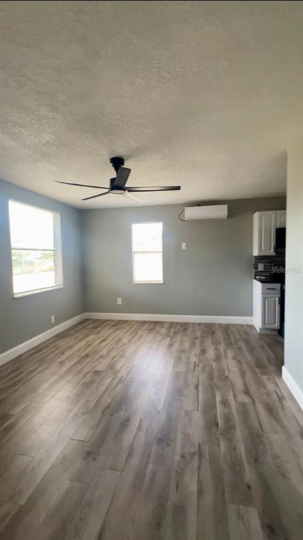 A room with light gray walls, wood-look flooring, a ceiling fan, and a mini-split unit — 708 MARTIN L KING JR AVENUE, LAKELAND, FL