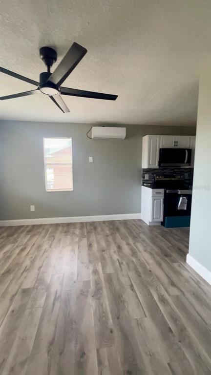 A room with light wood-look flooring, a ceiling fan, and an open kitchen area — 708 MARTIN L KING JR AVENUE, LAKELAND, FL