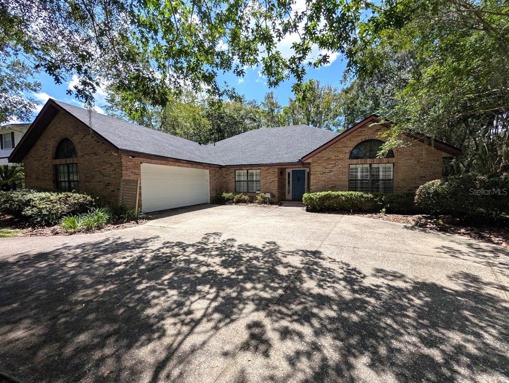 A single-story brick house with a two-car garage and a large concrete driveway — 6124 SW 35TH WAY, GAINESVILLE, FL
