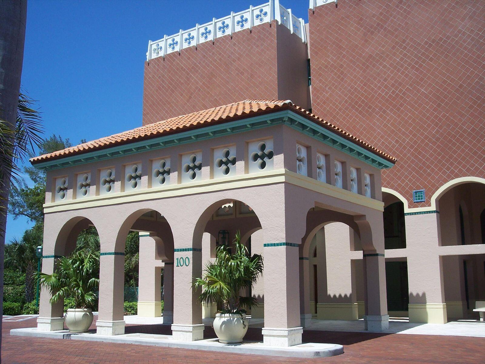 A pink stucco building features a covered entrance with arched columns and decorative tile accents — 100 SE 5th Avenue # 102, Boca Raton FL 33432, BOCA RATON, FL