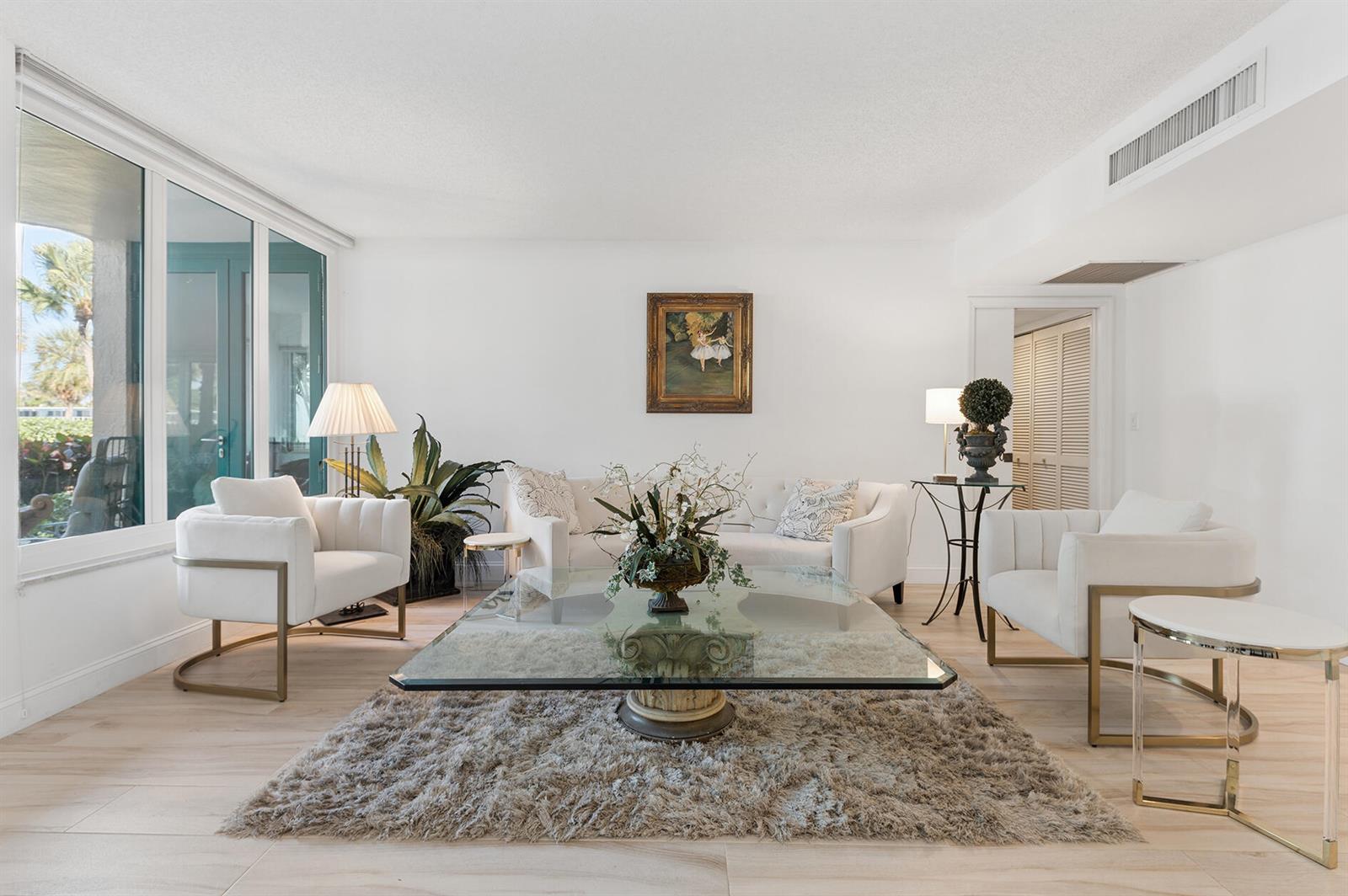 A bright living room features white furniture, a glass coffee table, and a shag rug — 100 SE 5th Avenue # 102, Boca Raton FL 33432, BOCA RATON, FL