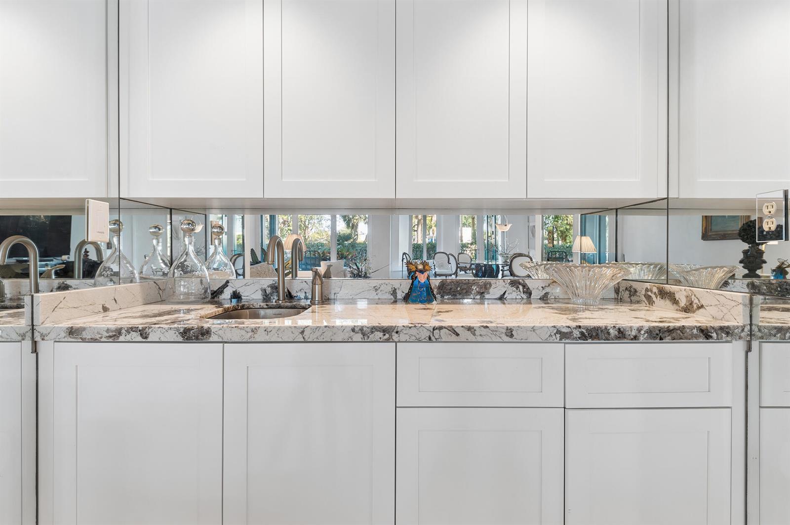 A wet bar features white cabinets, a marble countertop, and a mirrored backsplash — 100 SE 5th Avenue # 102, Boca Raton FL 33432, BOCA RATON, FL