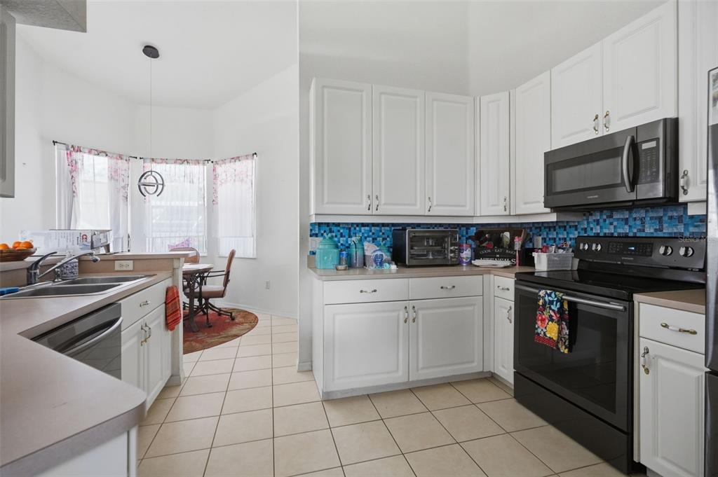 A kitchen with white cabinets, a blue mosaic tile backsplash, and black appliances — 15486 SARATOGA DRIVE, BROOKSVILLE, FL