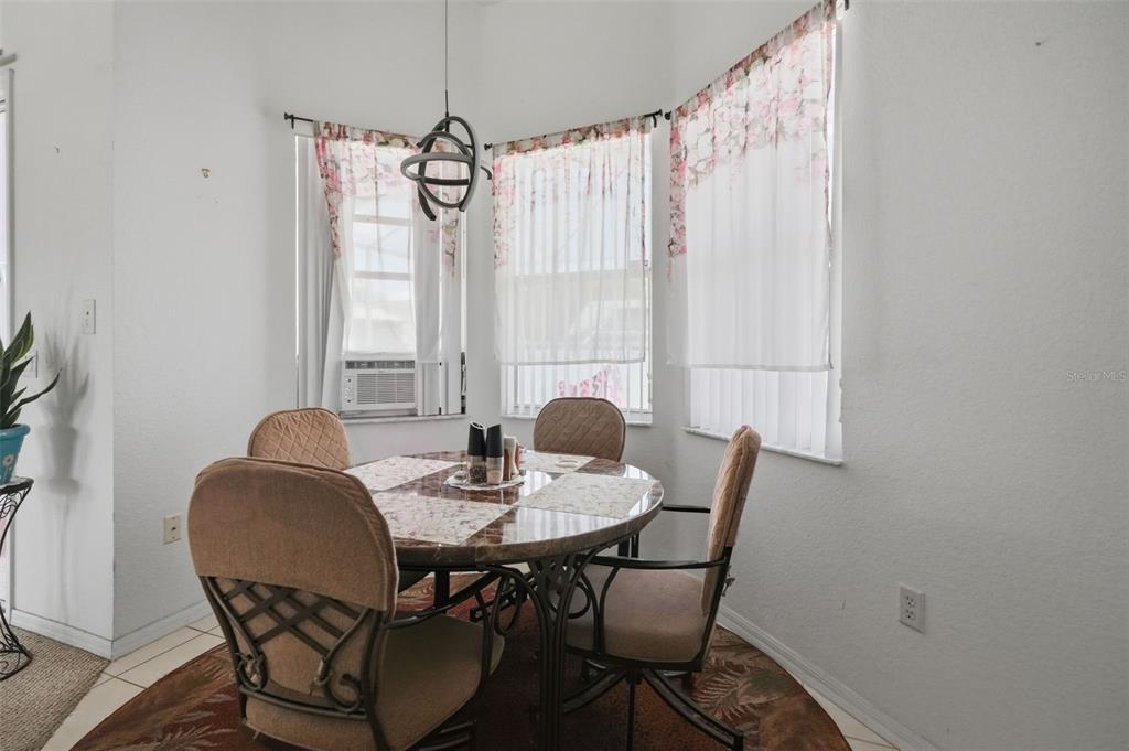 A dining area features a round table with four chairs under a hanging light fixture — 15486 SARATOGA DRIVE, BROOKSVILLE, FL