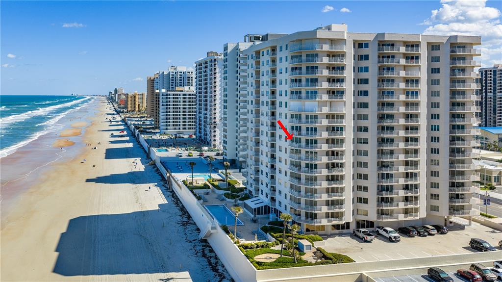 An aerial view shows a high-rise beachfront condominium building with a red arrow pointing toward a balcony — 2967 S ATLANTIC AVENUE UNIT 903, DAYTONA BEACH SHORES, FL