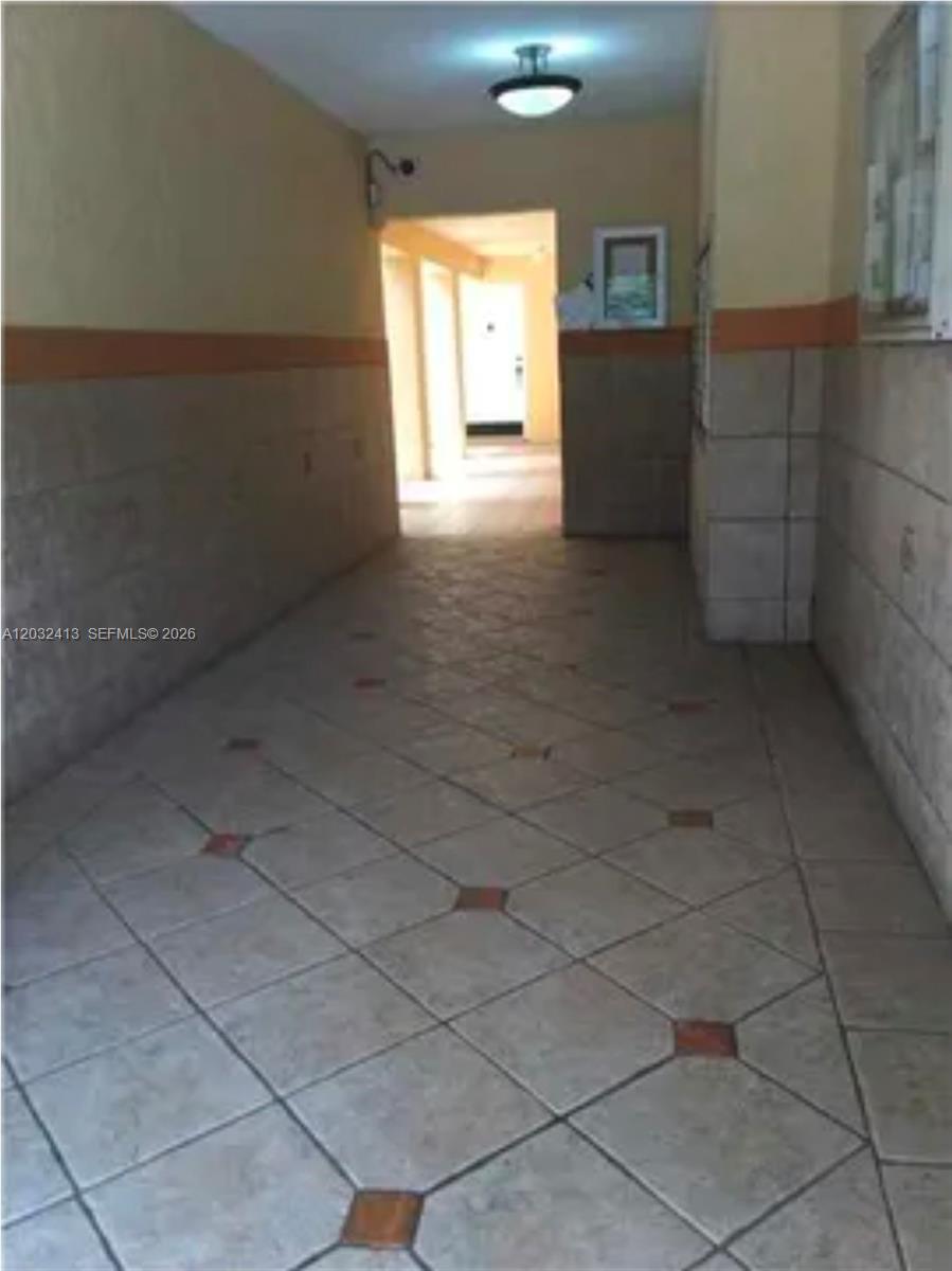 A tiled hallway leads toward an open doorway under a single ceiling light fixture — 5501 NW 7th St # E408, Miami FL 33126, MIAMI, FL