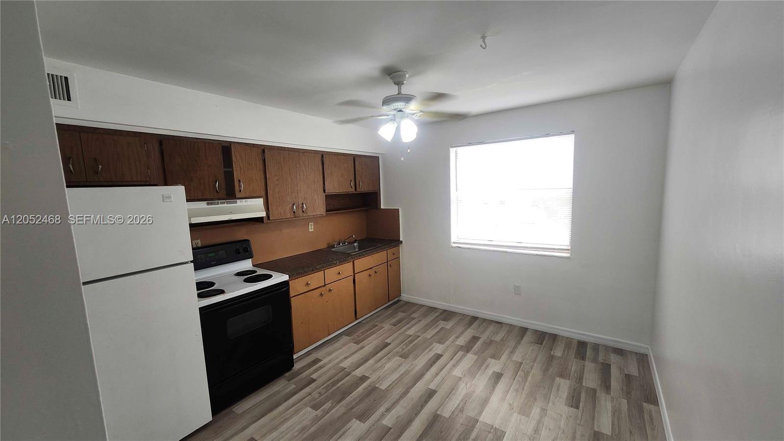 A kitchen features wood cabinets, a white refrigerator, a black stove, and wood-look flooring — 111 NW 152nd St # 16, Miami FL 33169, MIAMI, FL