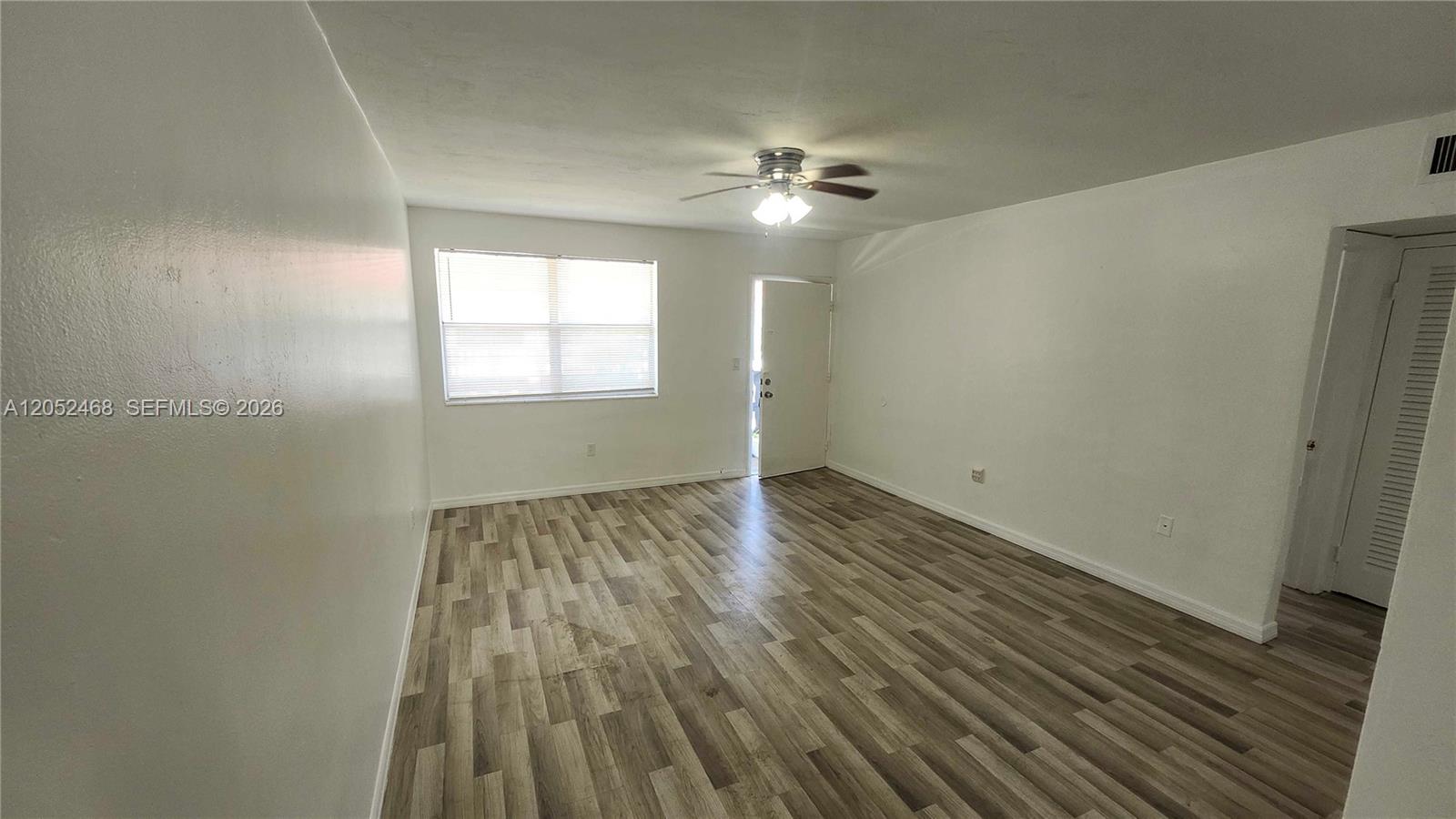 An empty room features white walls, a ceiling fan, and wood-look laminate flooring — 111 NW 152nd St # 16, Miami FL 33169, MIAMI, FL