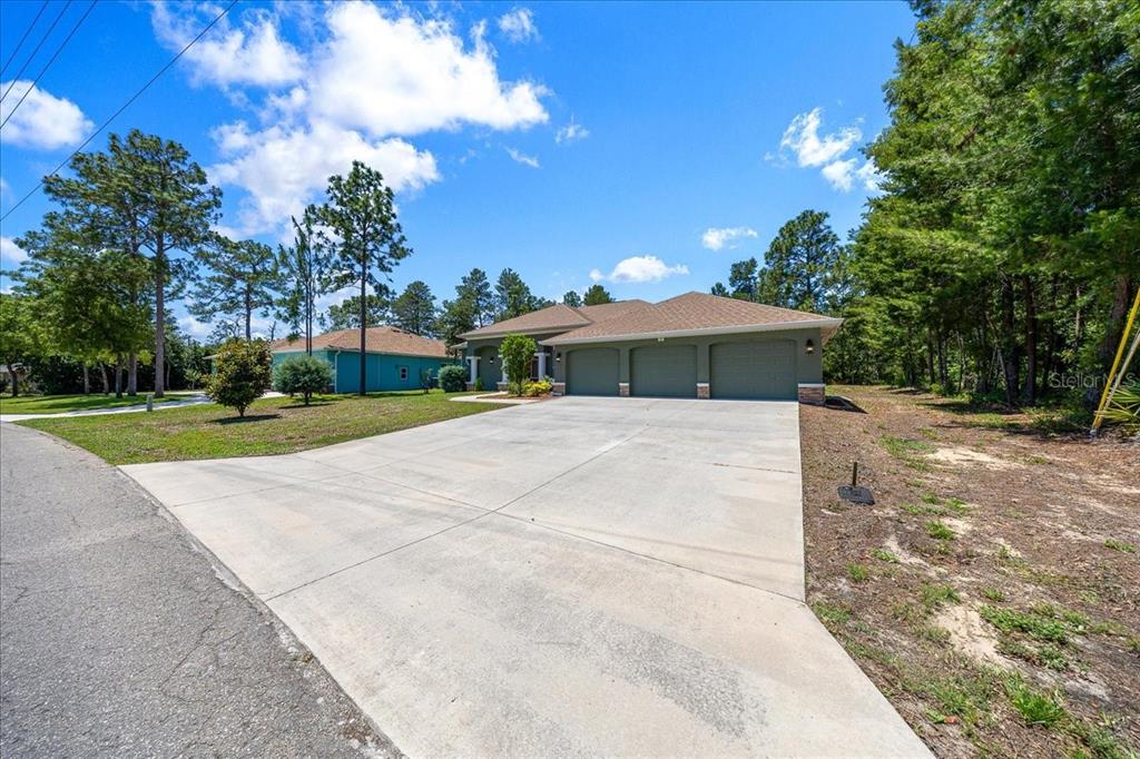A single-story house with a three-car garage and a large concrete driveway — 5 SAINTPAULIA STREET, HOMOSASSA, FL