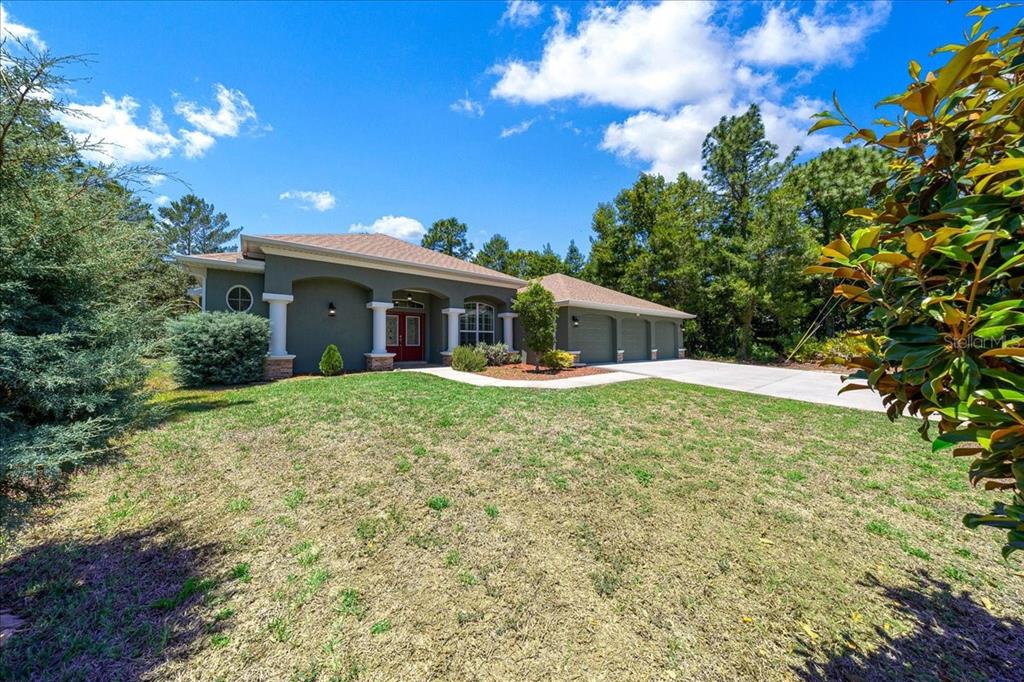 A single-story house with a gray exterior, a three-car garage, and a covered front porch — 5 SAINTPAULIA STREET, HOMOSASSA, FL