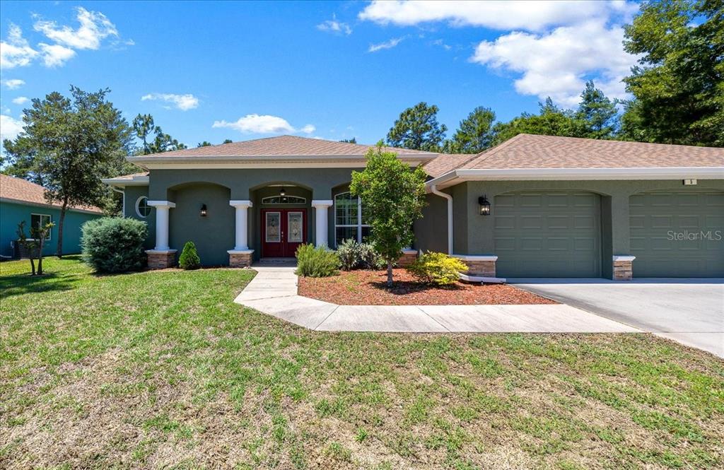 A single-story house with a green exterior, a two-car garage, and a red front door — 5 SAINTPAULIA STREET, HOMOSASSA, FL