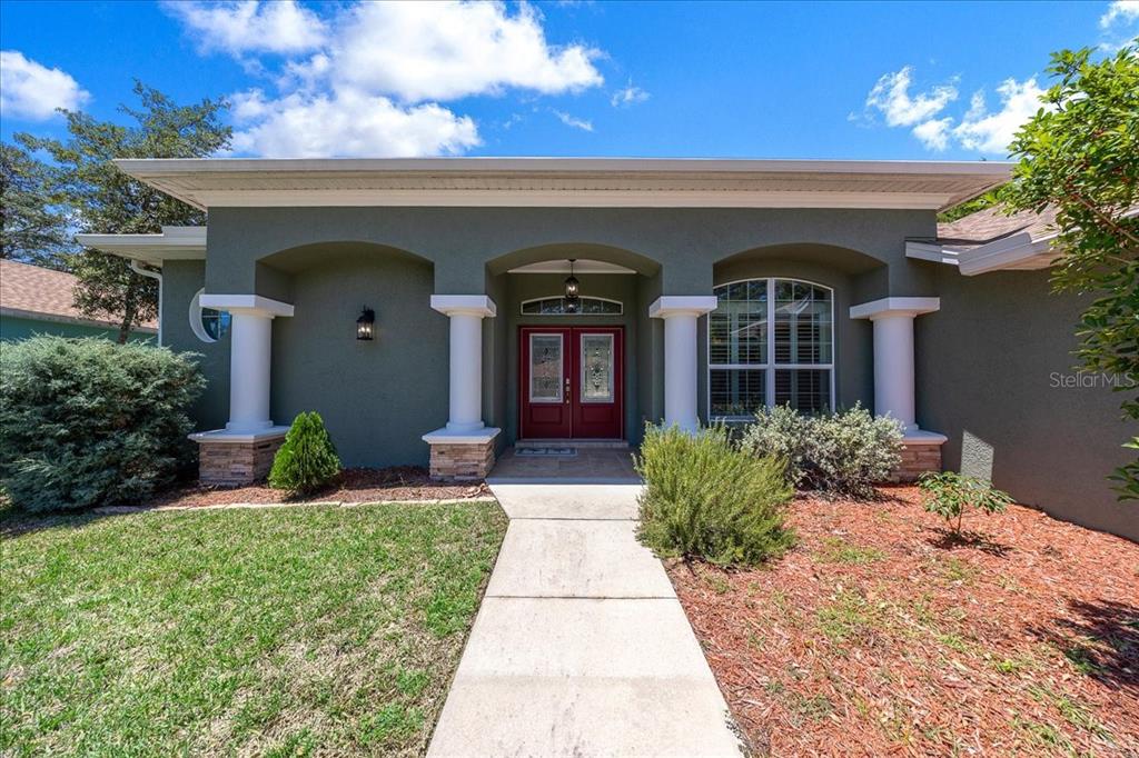 A single-story house exterior features a covered entryway with white columns and red double doors — 5 SAINTPAULIA STREET, HOMOSASSA, FL