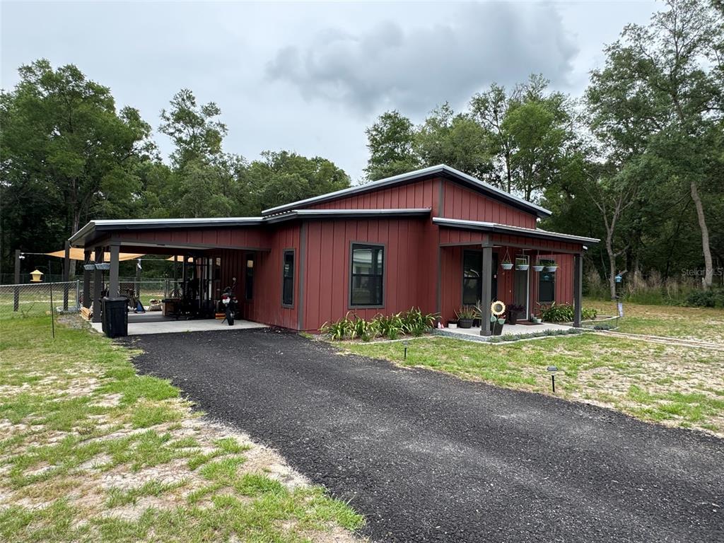 A red metal-sided house with a carport and a front porch sits on a lot — 8031 NW 172ND LANE, FANNING SPRINGS, FL