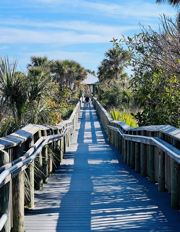 A wooden boardwalk with railings leads toward a covered pavilion surrounded by palm trees — 14307 HAYWARD AVENUE, PORT CHARLOTTE, FL