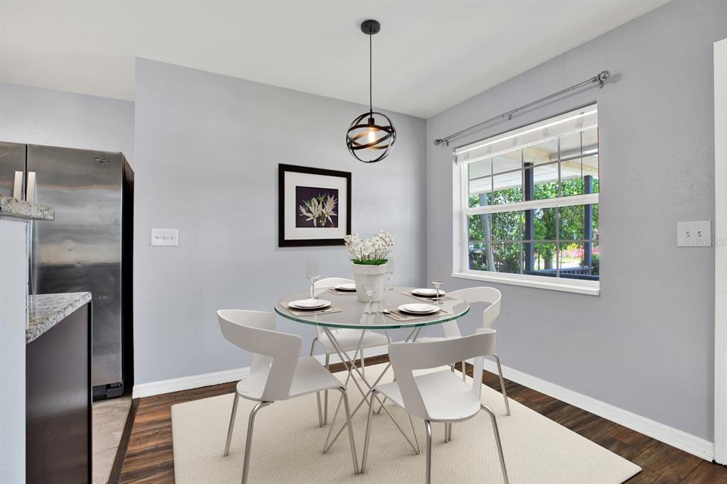 A dining area features a glass-topped table, four white chairs, and a modern pendant light — 3813 W WISCONSIN AVENUE, TAMPA, FL
