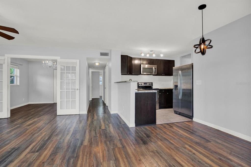 A kitchen with dark cabinets and stainless steel appliances opens to a living area — 3813 W WISCONSIN AVENUE, TAMPA, FL