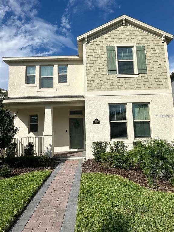 A two-story house with a beige stucco exterior, green shutters, and a brick walkway — 17865 ADRIFT ROAD, WINTER GARDEN, FL