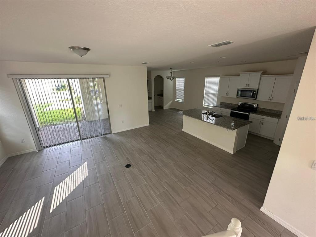An open-concept kitchen and living area feature gray wood-look tile flooring and sliding glass doors — 17865 ADRIFT ROAD, WINTER GARDEN, FL