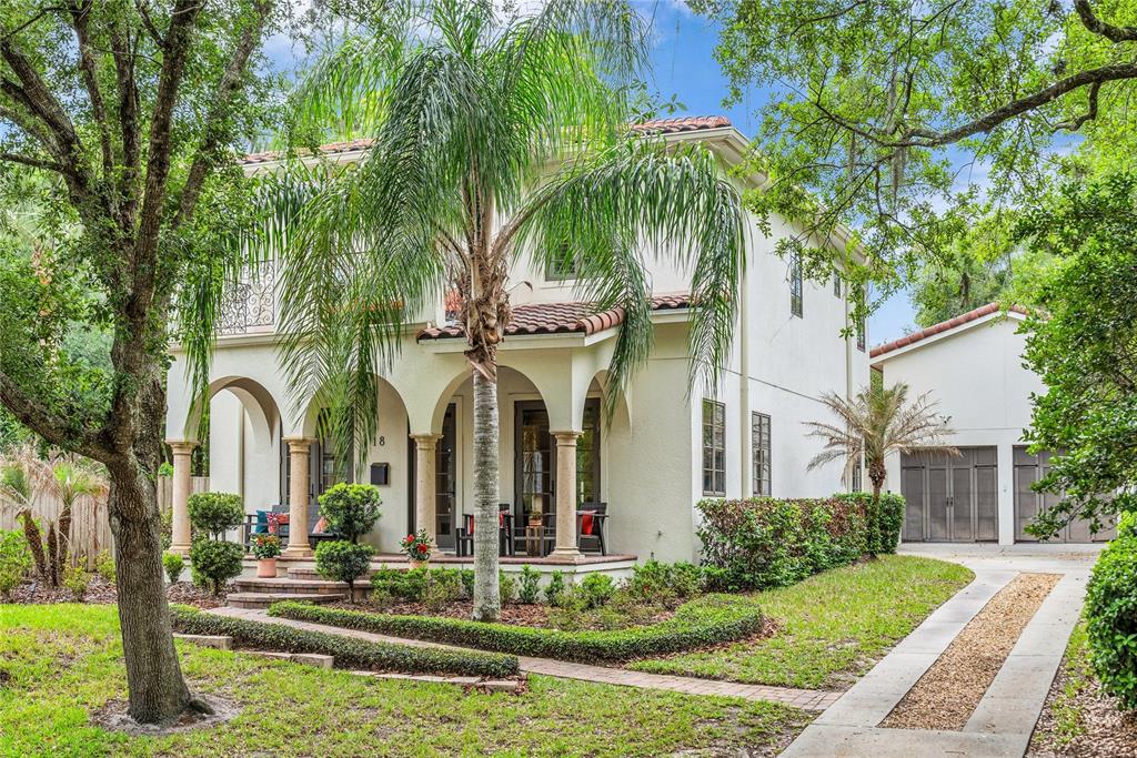 A two-story Mediterranean-style house with a covered front porch, palm tree, and detached garage — 18 CELIA LANE, ORLANDO, FL