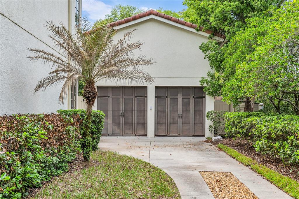 A two-car garage with wooden carriage-style doors sits at the end of a concrete driveway — 18 CELIA LANE, ORLANDO, FL