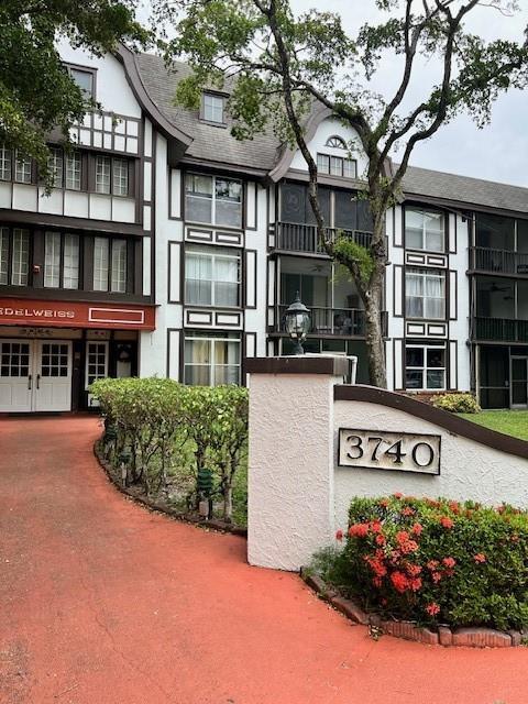 A multi-story Tudor-style apartment building features a red driveway and a prominent address sign — 3740 Inverrary Drive # 2u, Lauderhill FL 33319, LAUDERHILL, FL