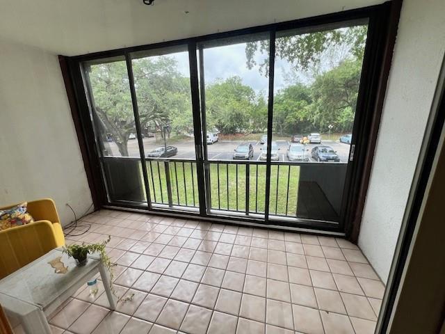 A sunroom features beige tile flooring, a yellow chair, and large sliding glass doors — 3740 Inverrary Drive # 2u, Lauderhill FL 33319, LAUDERHILL, FL