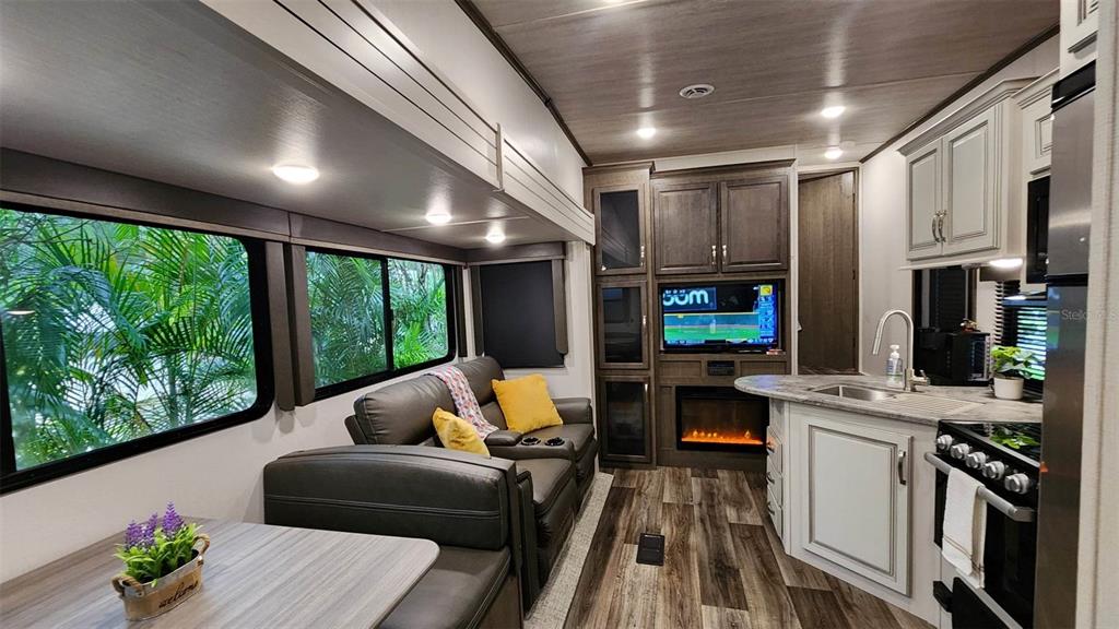 A modern RV interior featuring a living area with a sofa, fireplace, and kitchen island — 251 SADDLE LANE, LAKE WALES, FL