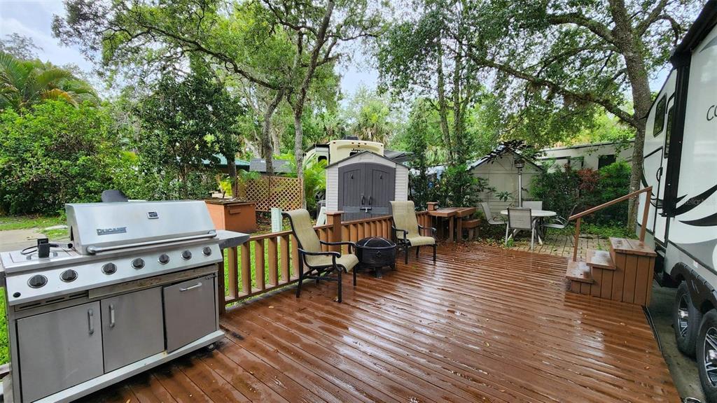 A wooden deck features a large stainless steel grill, patio chairs, and a storage shed — 251 SADDLE LANE, LAKE WALES, FL