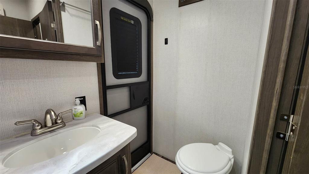 A bathroom with a vanity, sink, toilet, and a screen door leading outside — 251 SADDLE LANE, LAKE WALES, FL