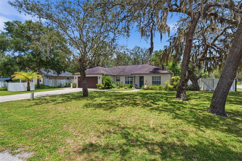 A single-story house with a brown roof and garage sits behind a large grassy yard — 11240 MARQUERITE AVENUE, NEW PORT RICHEY, FL