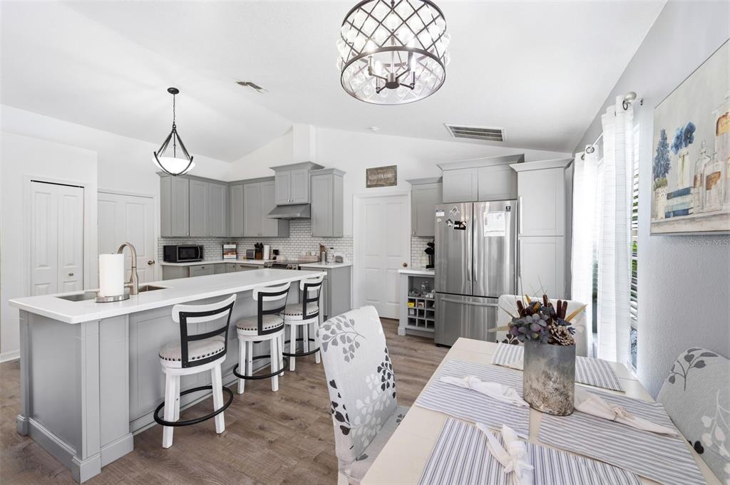 A kitchen and dining area with gray cabinets, a white island, and stainless steel appliances — 11240 MARQUERITE AVENUE, NEW PORT RICHEY, FL