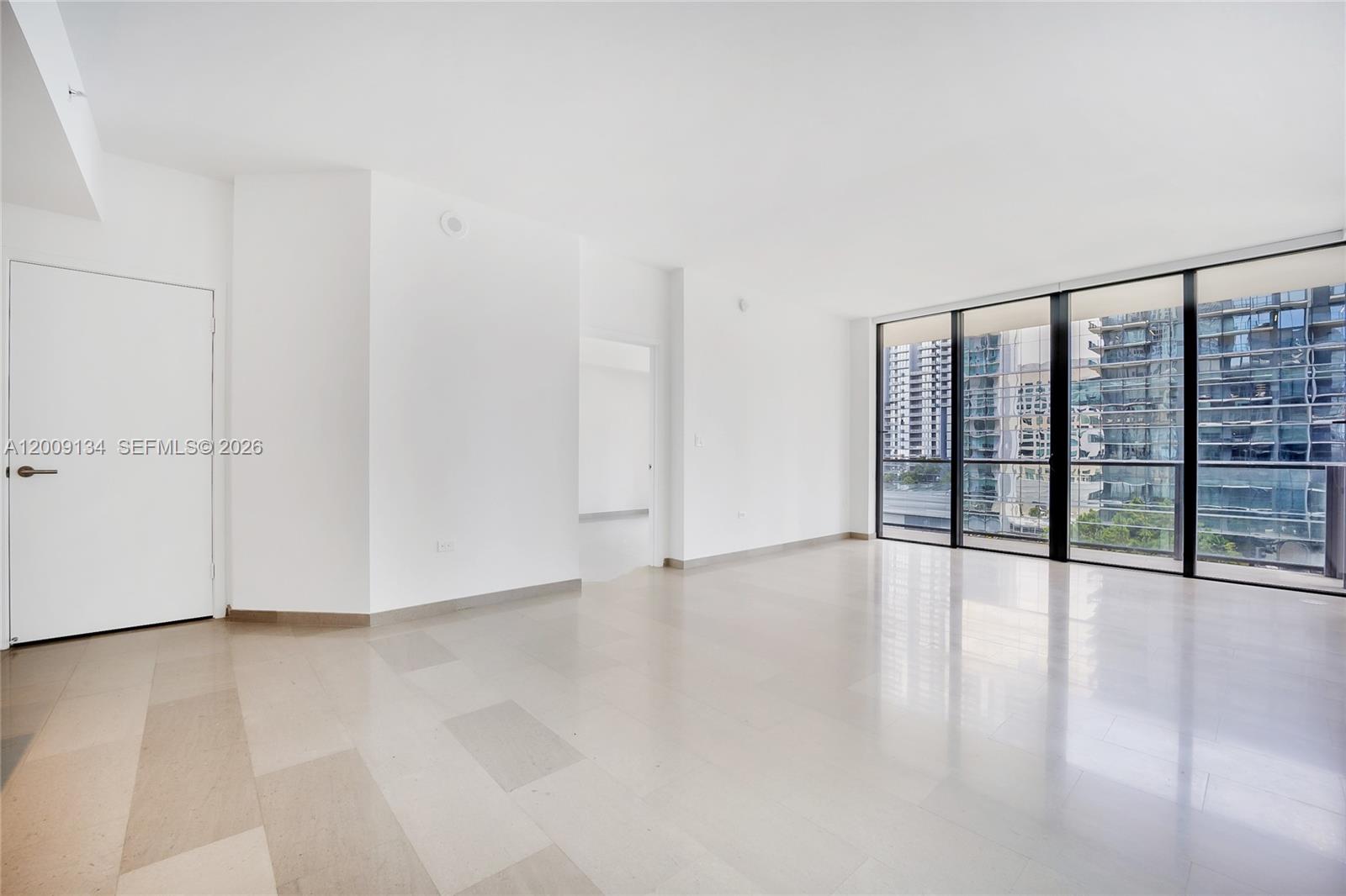 An empty room with white walls, light-colored tile flooring, and floor-to-ceiling windows — 88 SW 7th St # 1009, Miami FL 33130, MIAMI, FL
