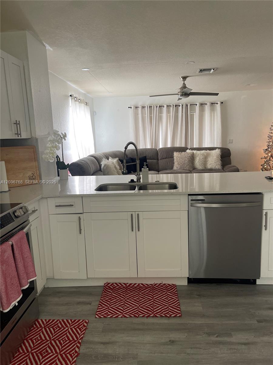 A kitchen with white cabinets and stainless steel appliances overlooks a living room with seating — 2432 SW 99th Way, Miramar FL 33025, MIRAMAR, FL