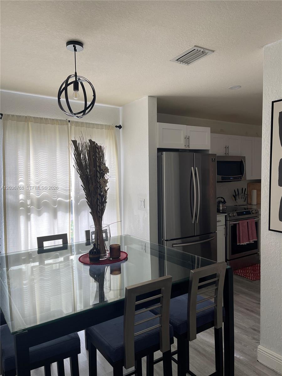 A dining area with a glass table and pendant light sits adjacent to a kitchen — 2432 SW 99th Way, Miramar FL 33025, MIRAMAR, FL