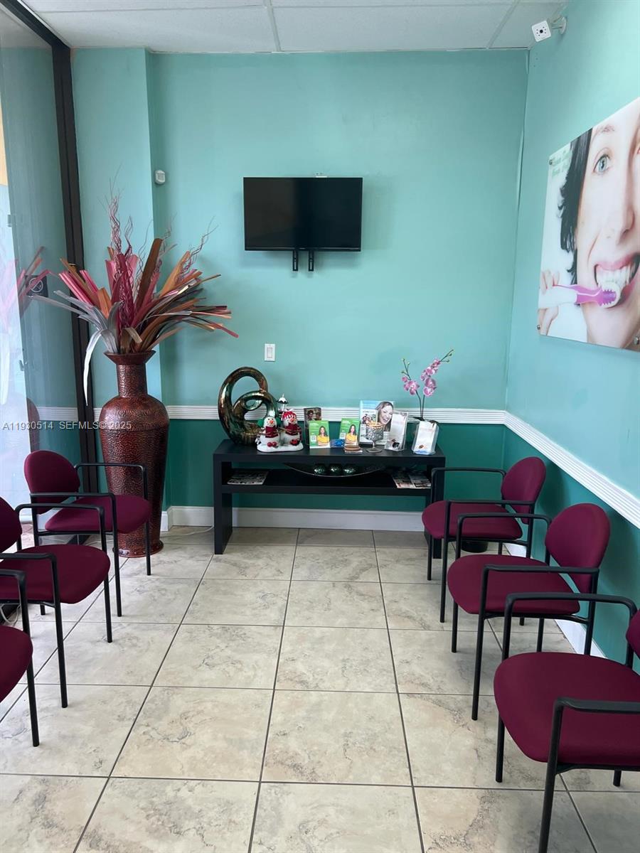 A waiting room features teal walls, maroon chairs, a television, and a decorative floor vase — 4750 NW 7 ST, Miami FL 33126, MIAMI, FL