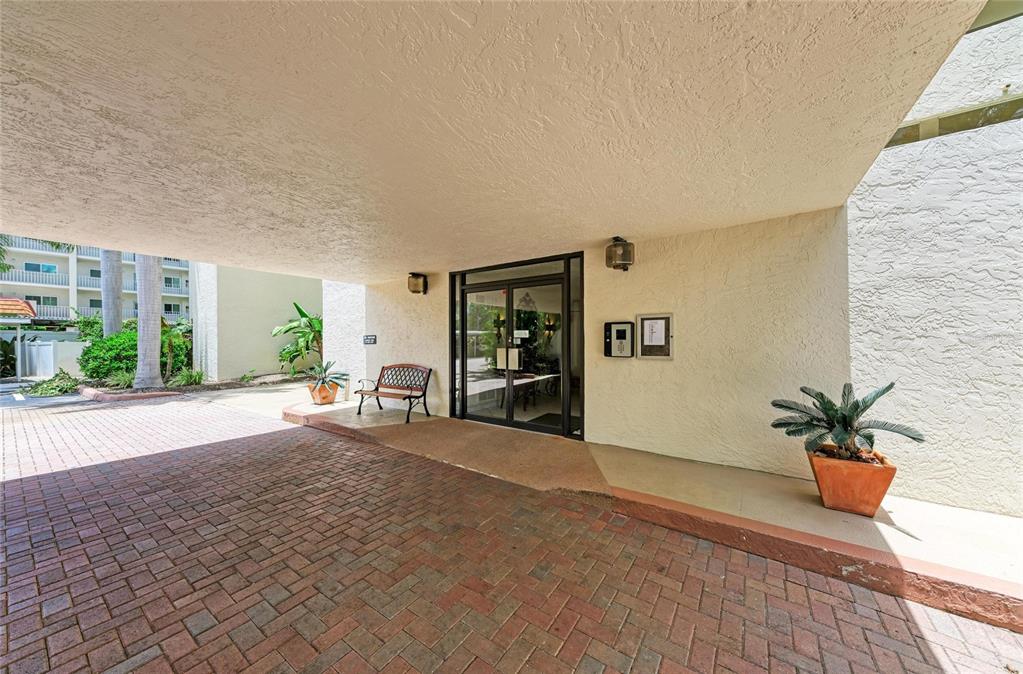 A covered entrance features a brick driveway, a glass door, and a small bench — 1510 1ST AVENUE W UNIT 503, BRADENTON, FL