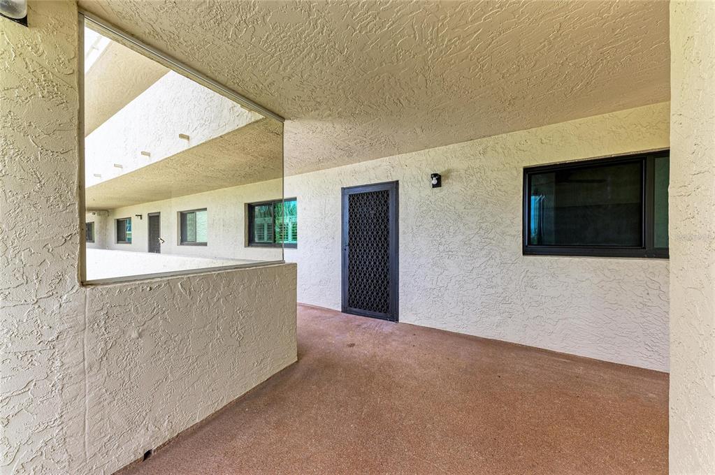 An exterior walkway with a textured wall, a screen door, and a large window — 1510 1ST AVENUE W UNIT 503, BRADENTON, FL