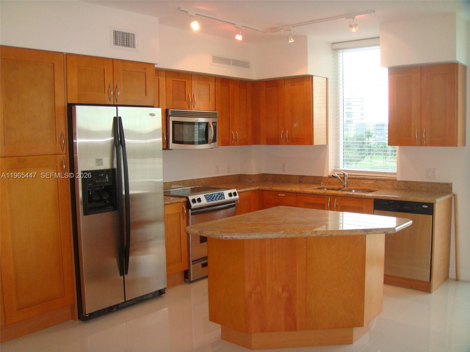 A kitchen features wood cabinets, granite countertops, stainless steel appliances, and a central island — 1755 E Hallandale Beach Blvd # 406E, Hallandale Beach FL 33009, HALLANDALE BEACH, FL